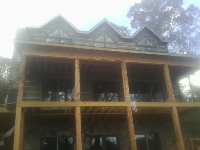 Dormers and porch framing on a large log home under construction — Roof Coating work by our crew in Canon