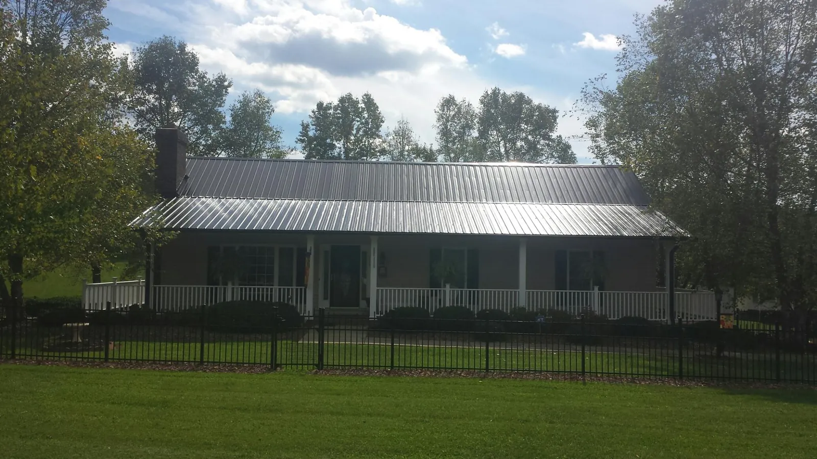 Gray metal roof on a brick ranch with a full width front porch — Gutter Guard Installation work by our crew in Canon